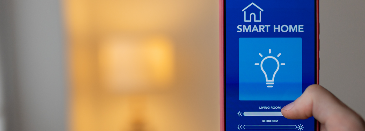 Slimme verlichting in huis: telefoon met bedieningsscherm en op de achtergrond een lamp die aan staat