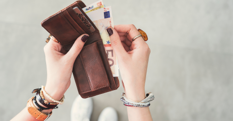 Prinsjesdag koopkracht; vrouw heeft een portomonnee in haar hand en haalt er briefgeld uit