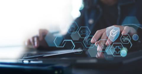 Zakenman achter laptop met icoontjes van verschillende verzekeringen